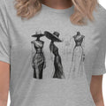 Woman wearing a gray t-shirt with black graphics of women and dresses on a white background.